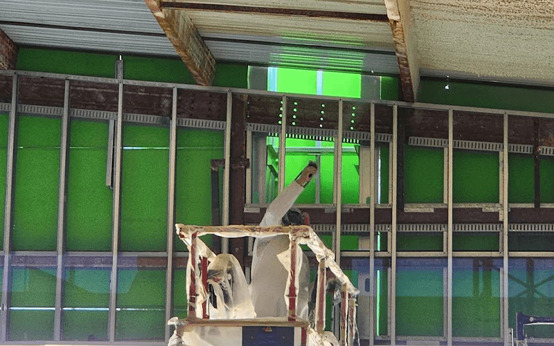 Construction worker installing green panels in senior living community building.